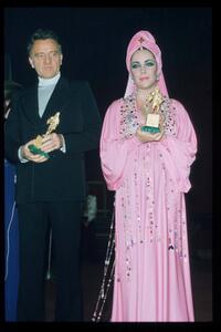 Richard Burton and Elizabeth Taylor hold award statuettes in Italy.