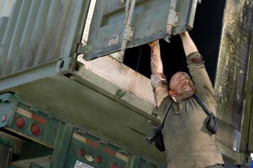 A battered and bloodied John McClane (Bruce Willis) holds on for dear life in "Live Free or Die Hard."