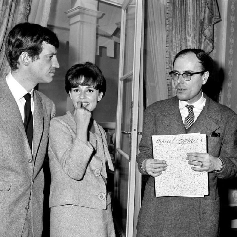 Jean-Paul Belmondo, Jeanne Moreau and Marcel Ophuls during a cocktail in Paris.