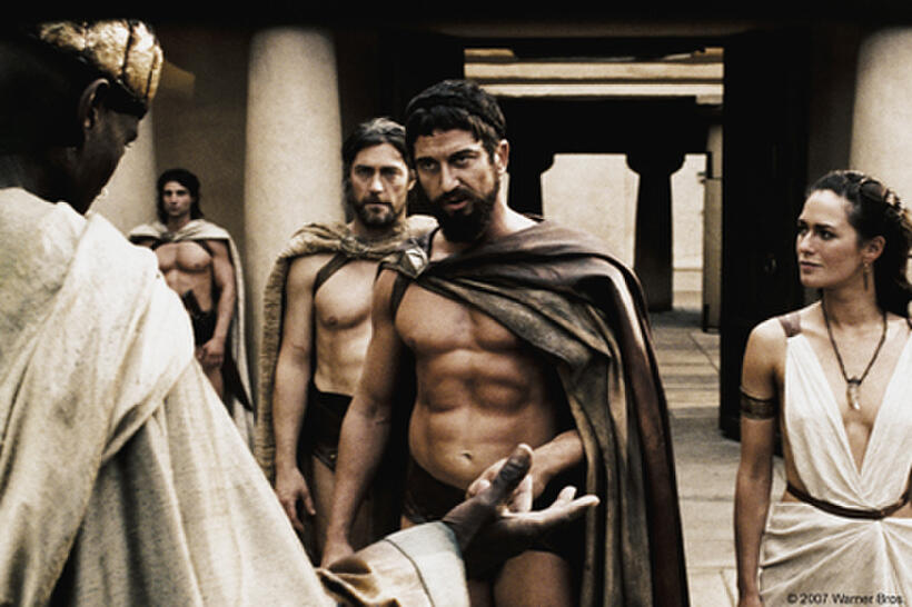 Leonidas (Gerard Butler) warns the Persian Messenger (Peter Mensah) as Captain (Vincent Regan) and Gorgo (Lena Headey) look on in "300."