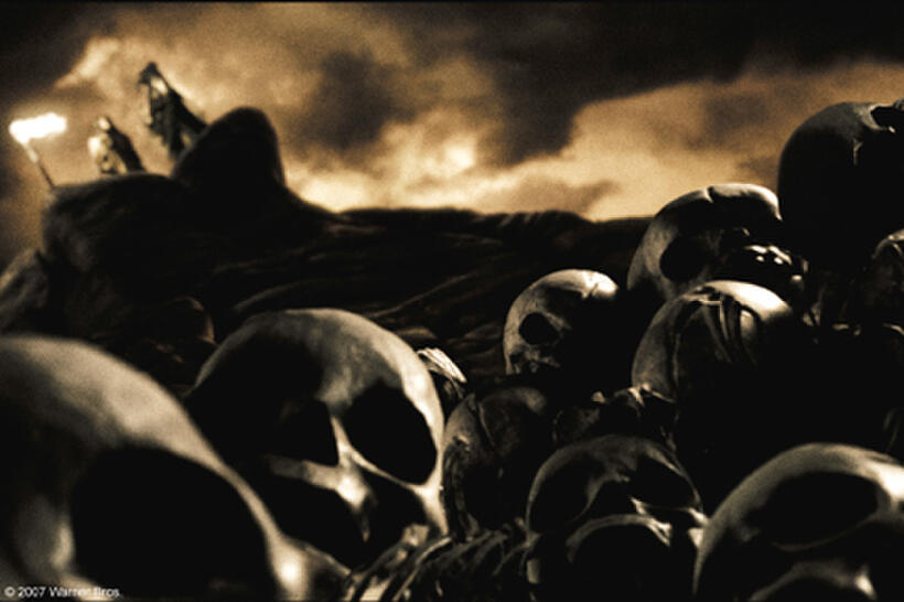 The Spartan Baby Inspector (Dennis St. John) standing atop Mt. Taygetos, examines the infant Leonidas for defects amid the remains of those deemed unworthy of becoming a Spartan in "300."
