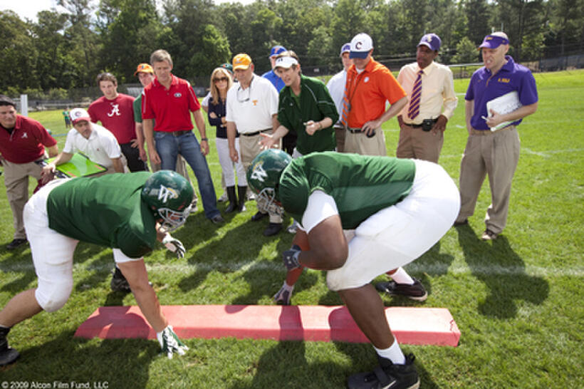 Sandra Bullock (center) as Leigh Anne Tuohy, Phillip Fulmer (center, orange hat) as himself, Ray McKinnon (center, visor) as Coach Cotton and Quinton Aaron (right foreground) as Michael Oher in "The Blind Side."